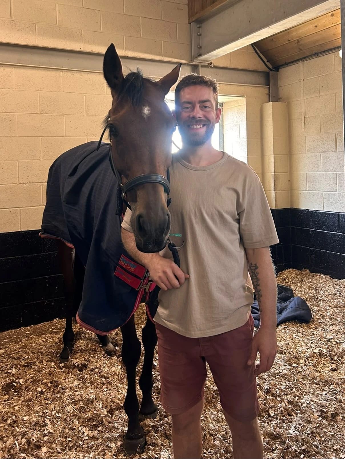 Jason in a stable with a bay horse in a rug